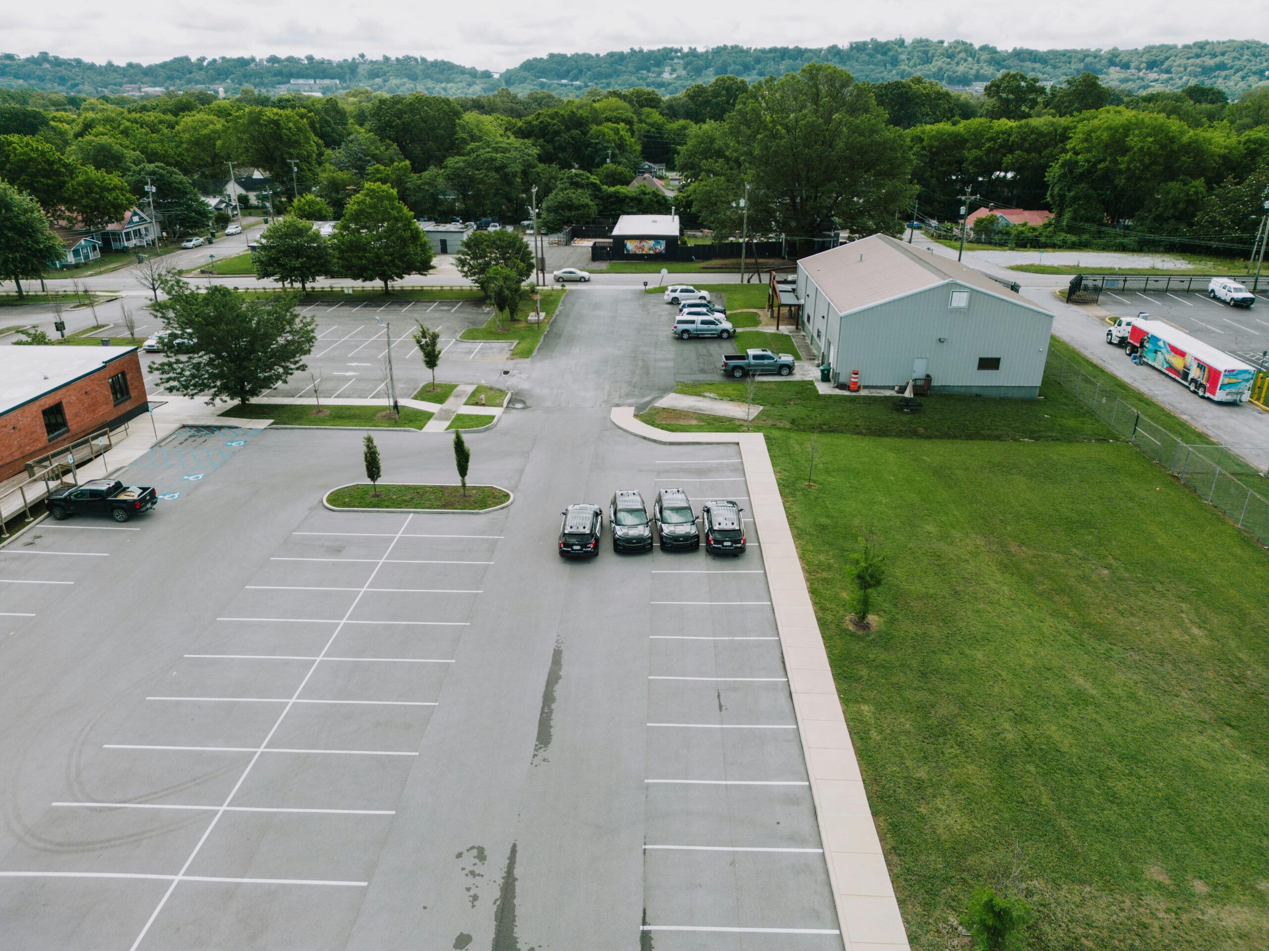 Drone shot of a parking lot in Chattanooga with cars and buildings, surrounded by lush greenery.