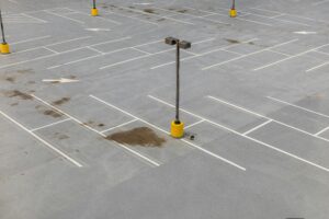 Aerial view of a spacious empty parking lot with visible white lines and lamp posts.