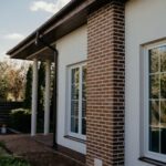 Charming modern house with brick features, glass windows, and lush garden.